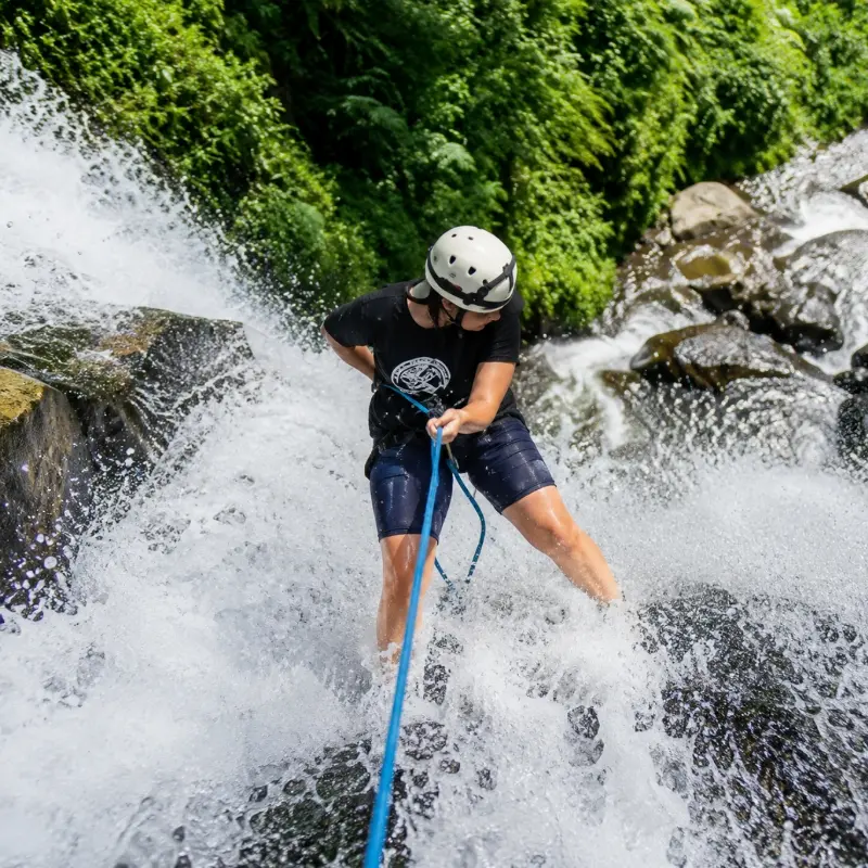 Peserta open trip canyoneering Curug Cikondang sedang melakukan rappelling di tebing air terjun