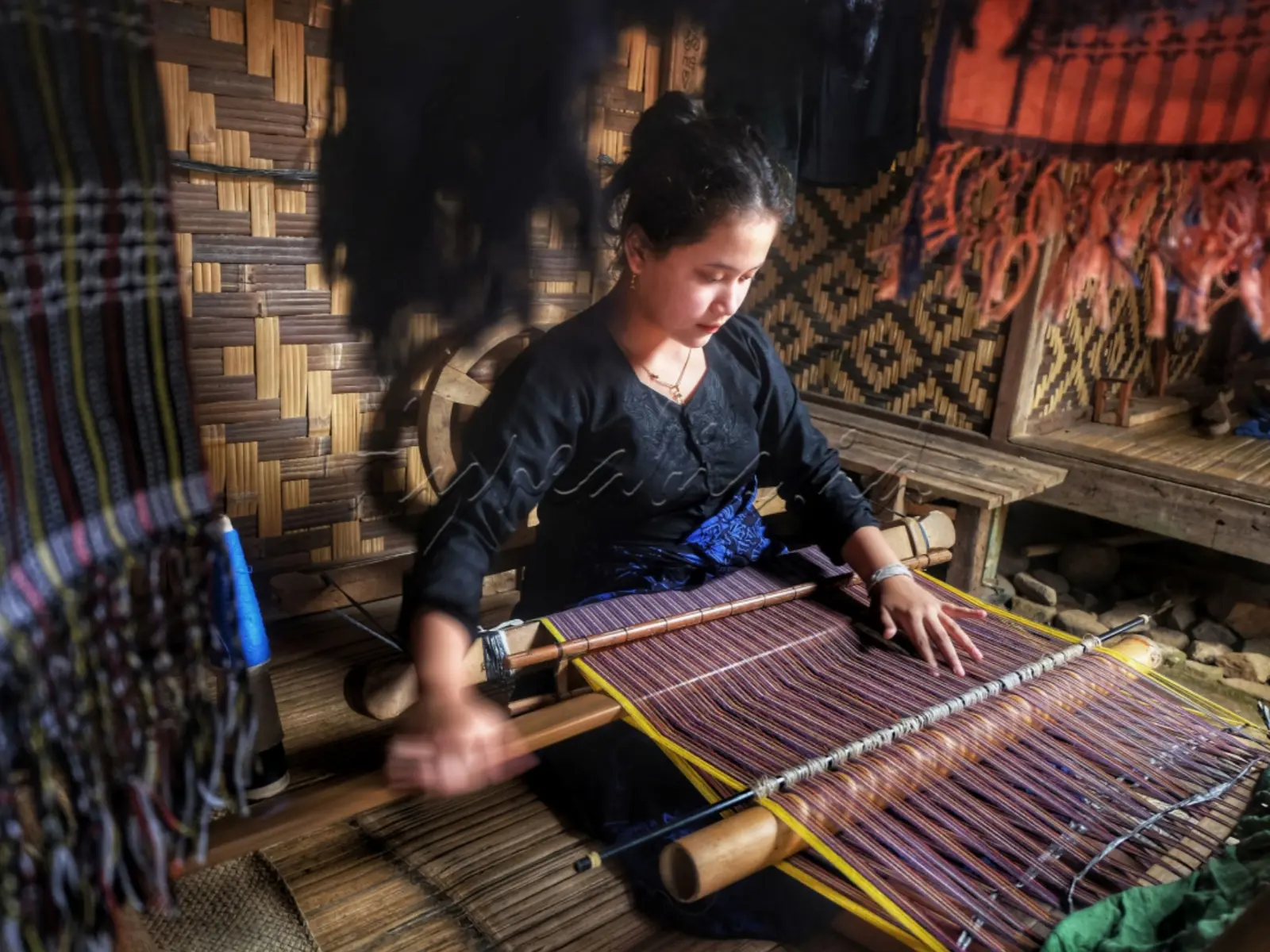 International travelers on a Private Baduy Luar Day Trip experiencing traditional cloth weaving in Baduy Luar